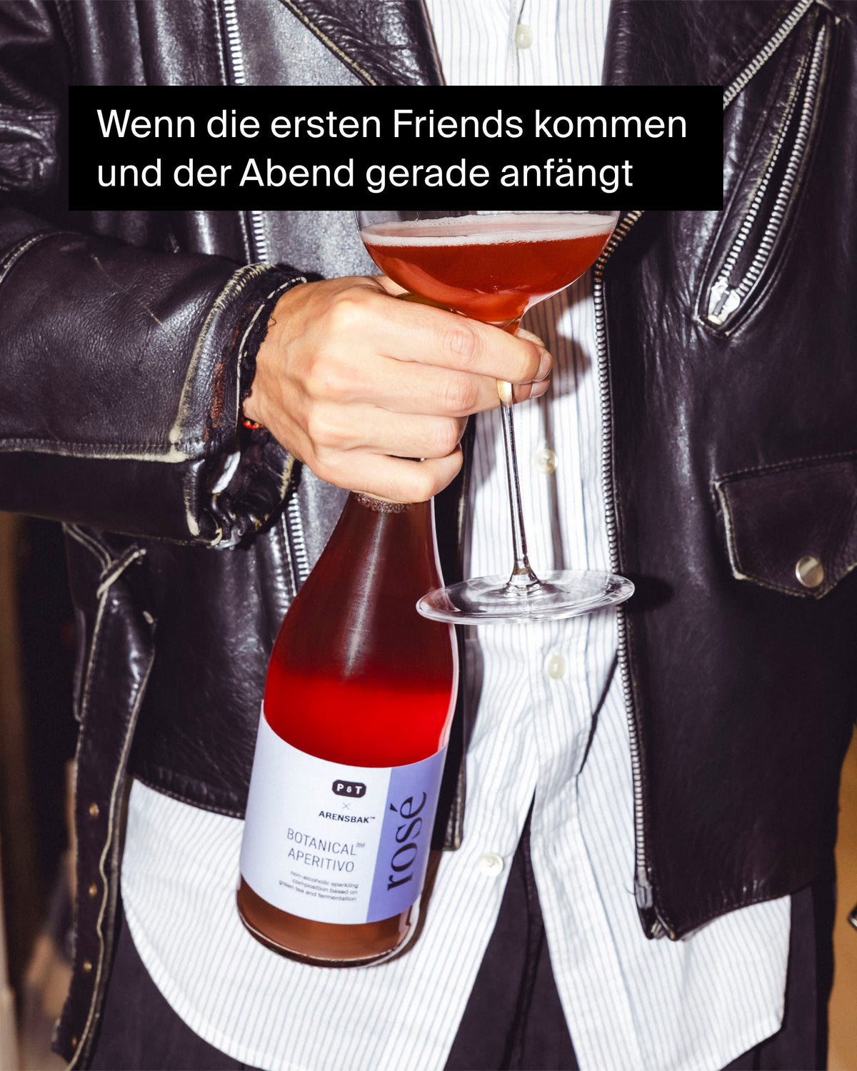 Person in schwarzer Lederjacke hält eine Flasche P&T Arensbak Aperitivo Rosé und ein Cocktailglas.