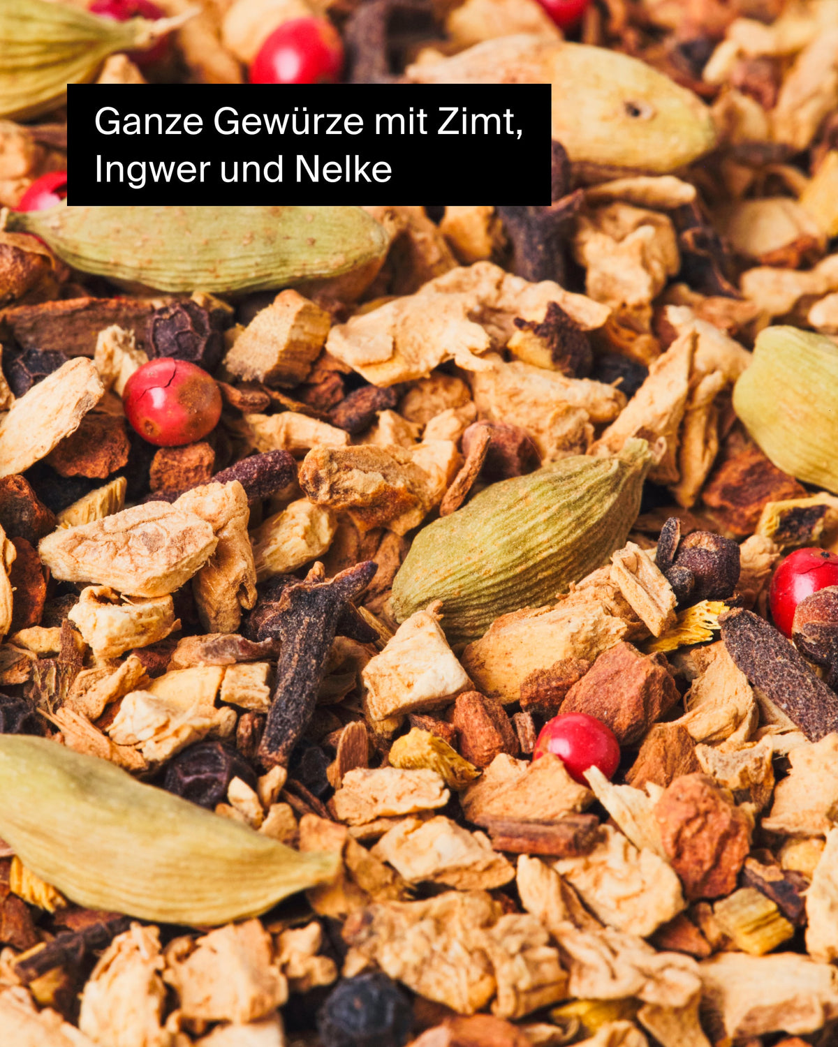 Nahaufnahme von Zimtstangen, Ingwer, Nelken, Kardamom und roten Pfefferkörnern.