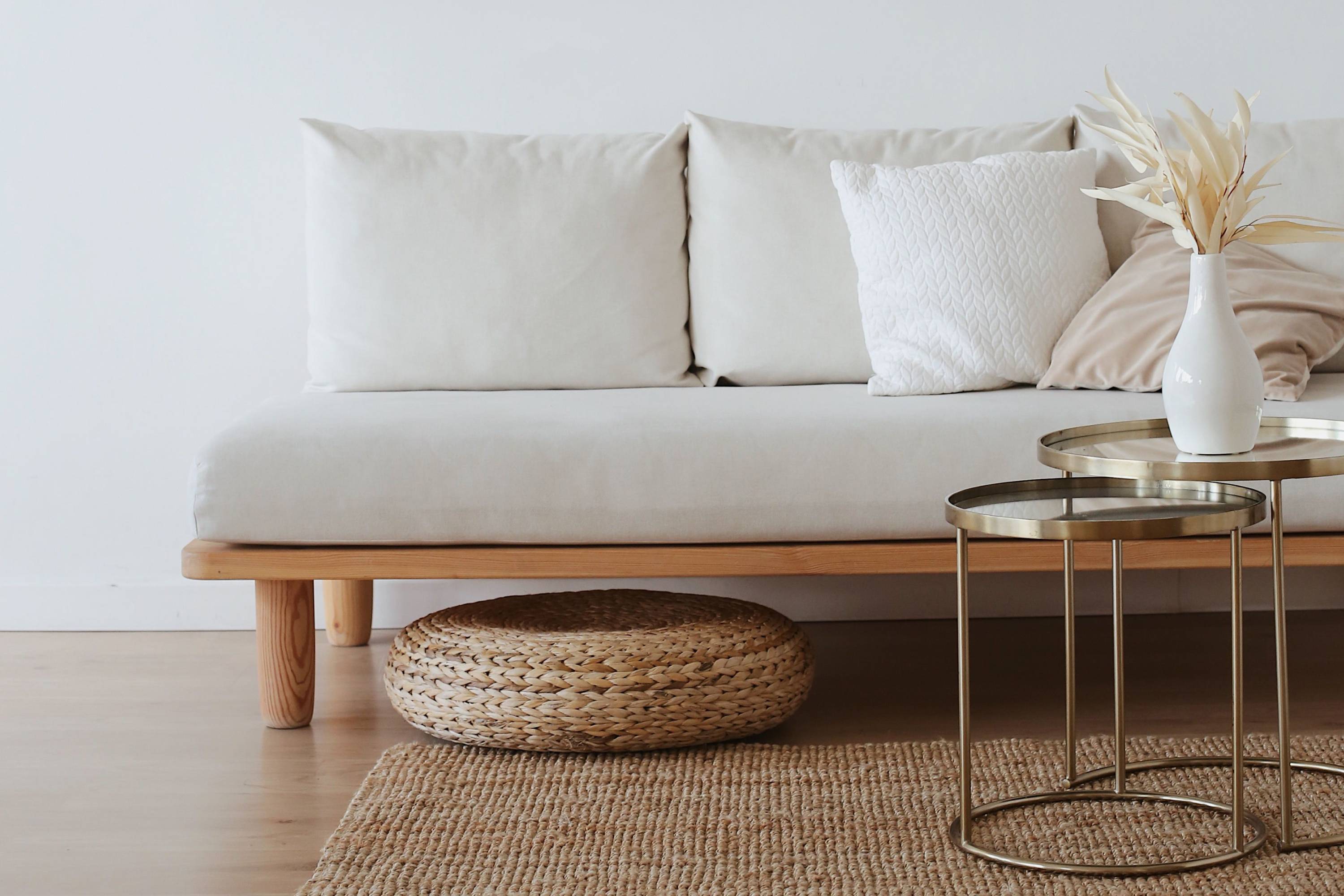 Beiges Sofa mit Kissen, goldene runde Tische im minimalistischen Wohnzimmer