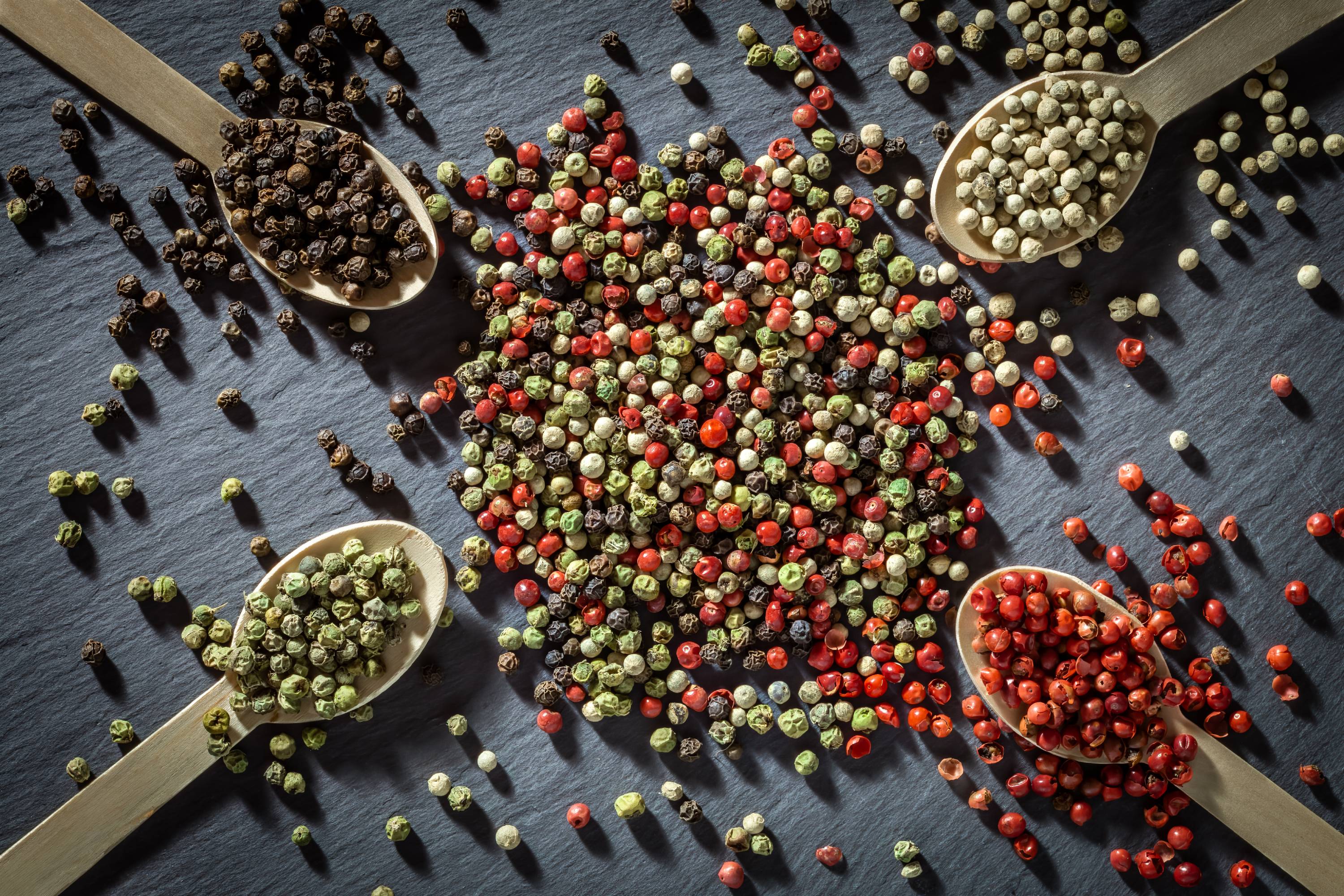 Bunte Pfefferkörner in vier Holzlöffeln