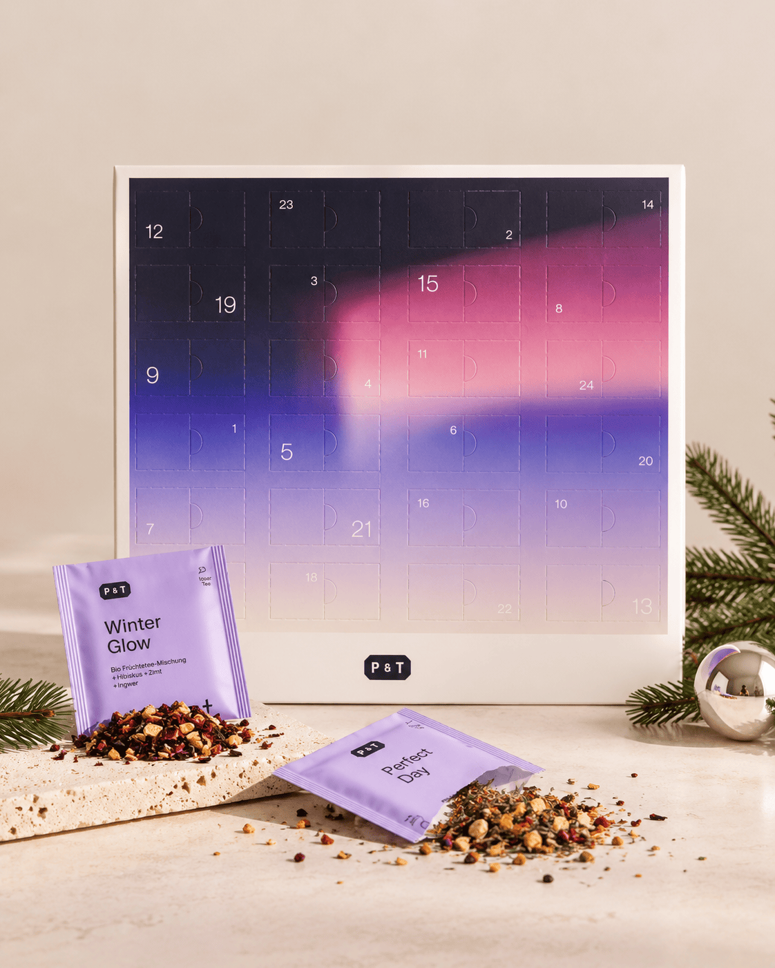 Stilvoller Adventskalender von P&T in Violett mit 24 Türen, zwei Teebeutel, Tannenzweige und silbernem Ornament.