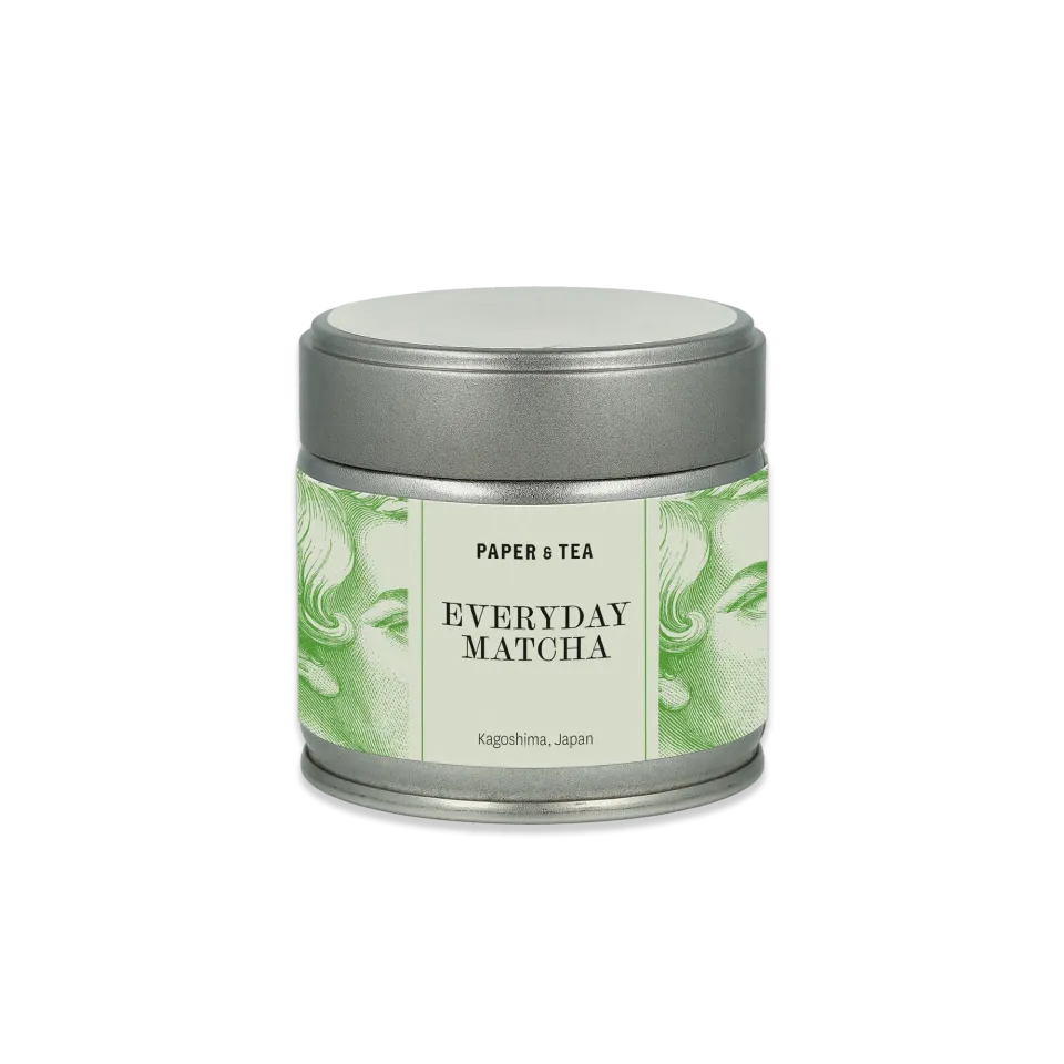 Metallischer Teebehälter mit Aufschrift 'PAPER & TEA Everyday Matcha Kagoshima, Japan', grüne Gesichter.