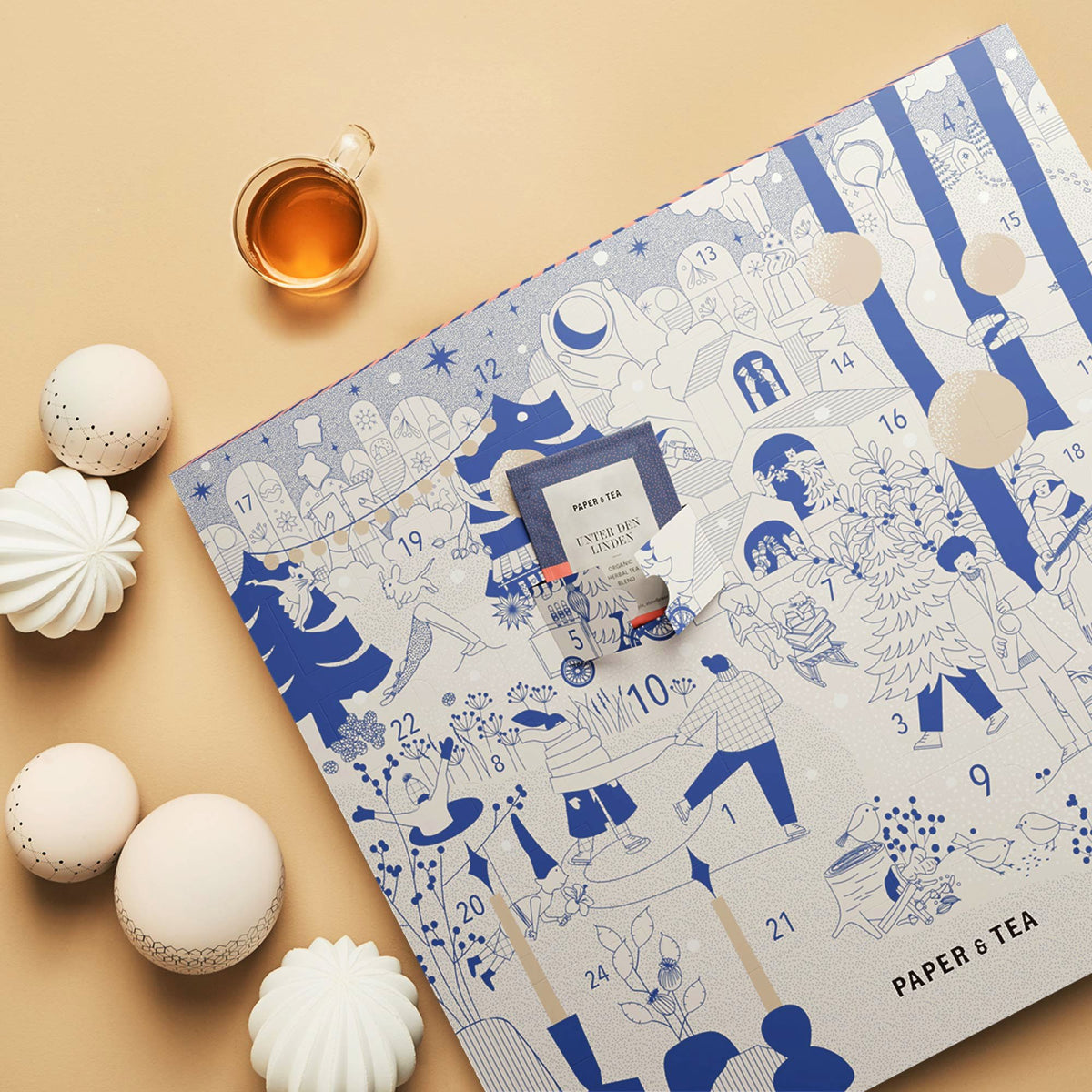 Adventskalender mit blau-weißen Zeichnungen, Türchen mit 'PAPER & TEA UNTER DEN LINDEN Bio-Kräutertee'.