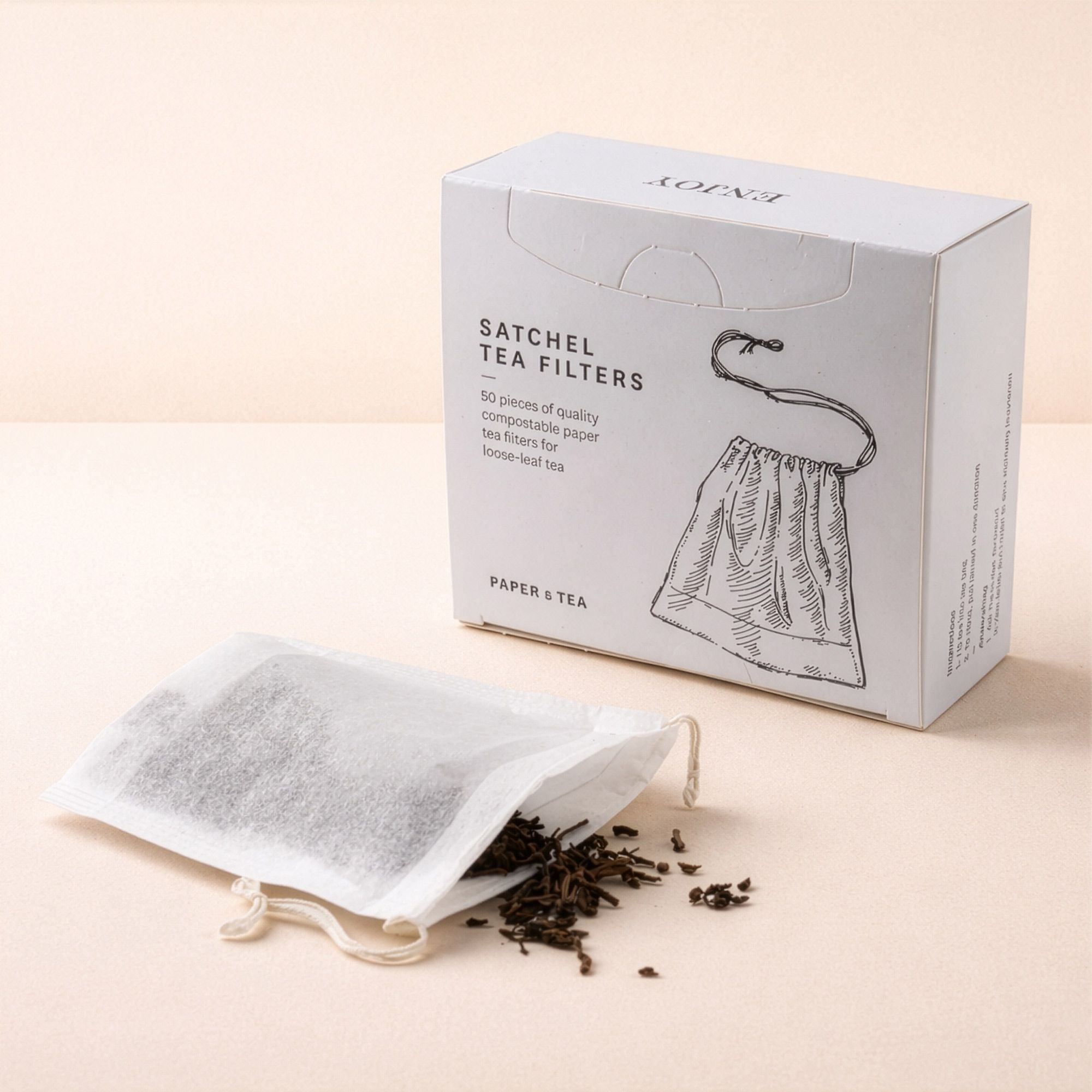 Kompostierbare weiße SATCHEL Teefilter auf beigem Hintergrund, offener Filter mit losem Tee.