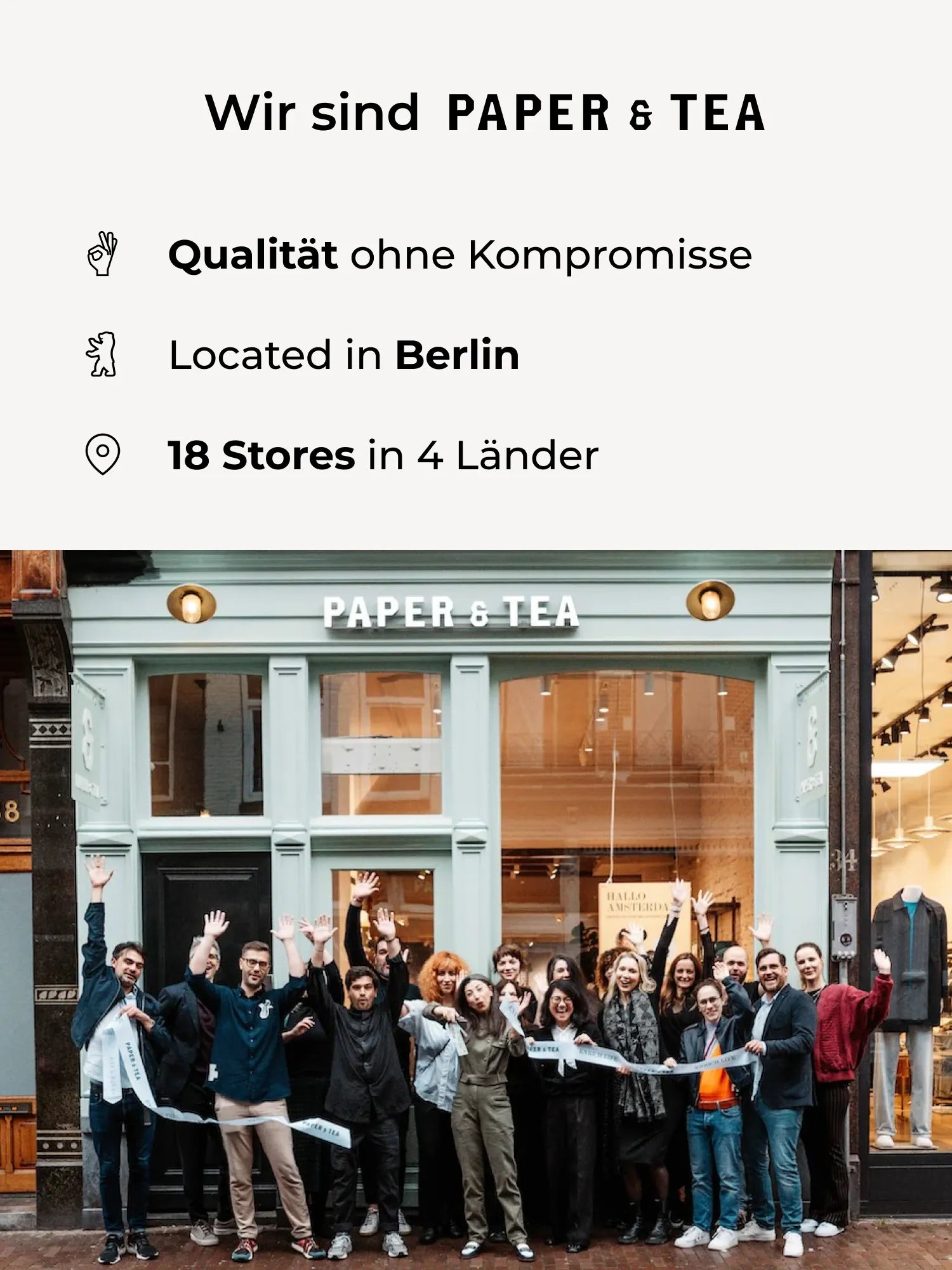 Fröhliche Gruppe vor dem PAPER & TEA Laden mit Qualität- und Standortbeschriftungen.
